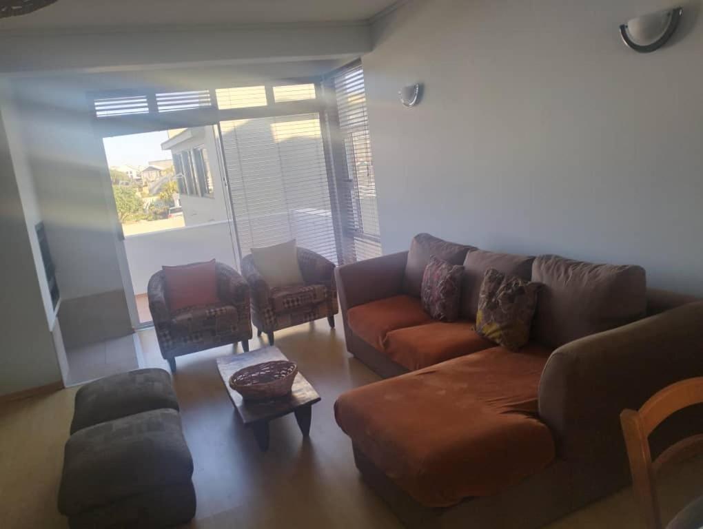 een woonkamer met een bruine bank en stoelen bij On the Beach 20 in Swakopmund