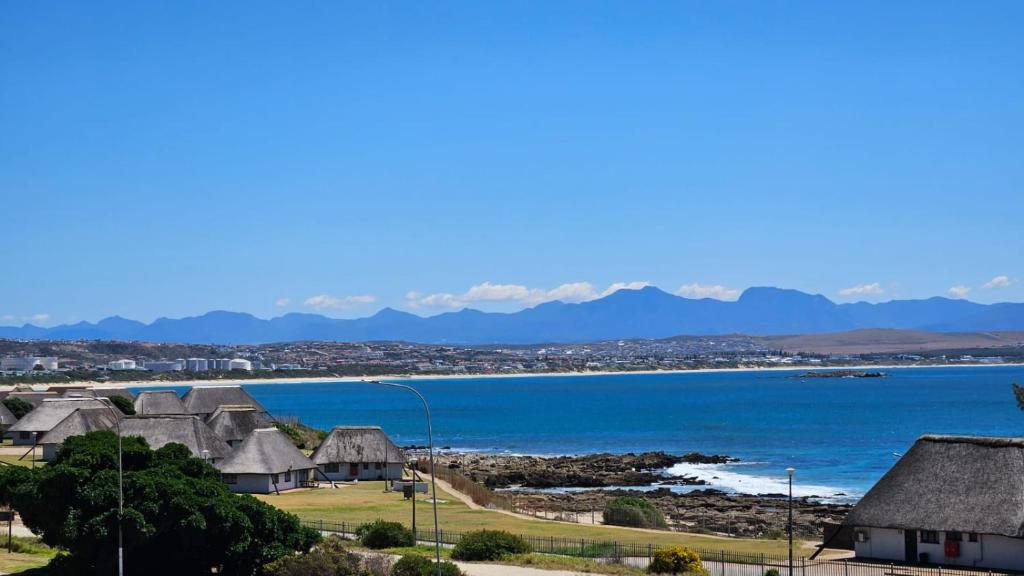 a view of a village with the ocean and mountains at Nautica 009 Studio Flat in Mossel Bay