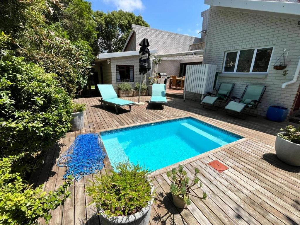 a swimming pool on a wooden deck next to a house at SeaSalt Escape in Plettenberg Bay