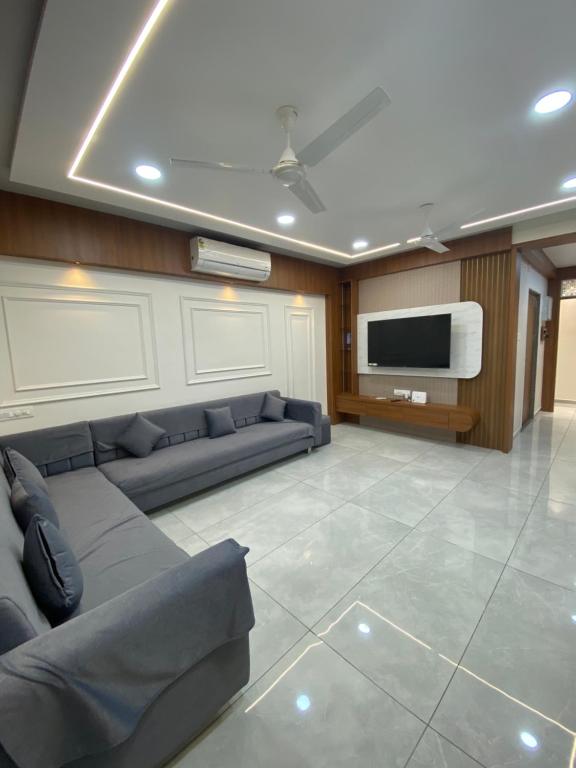 Una sala de estar con un sofá y un televisor de pantalla plana. en Home away from Home close to Swaminarayan Temple, en Nadiād