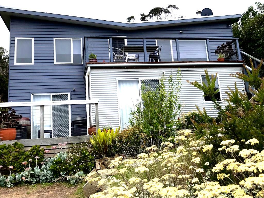 a blue house with a balcony and flowers at The Seaside Studio Retreat in Wye River