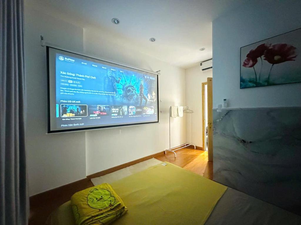 Zimmer mit einem Flachbild-TV an der Wand in der Unterkunft Homestay Máy chiếu vs Ban công ngắm thành phố - Marina Plaza in Ấp Ðông An (1)