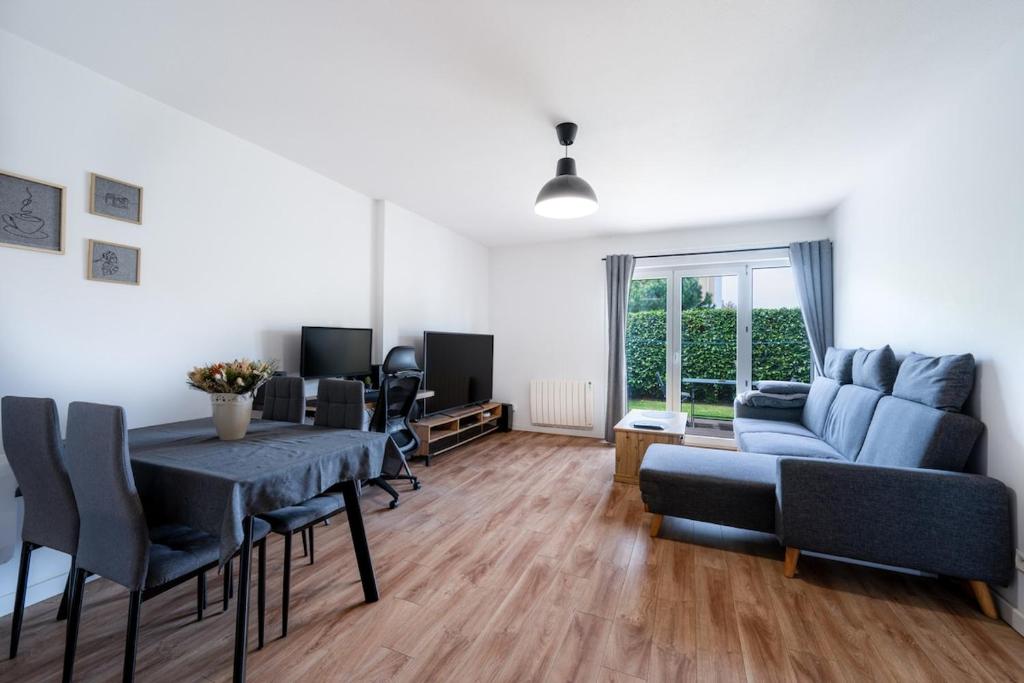 ein Wohnzimmer mit einem blauen Sofa und einem Tisch in der Unterkunft Chez Adrien au Haillan Appt rez de chaussée jardin in Le Haillan