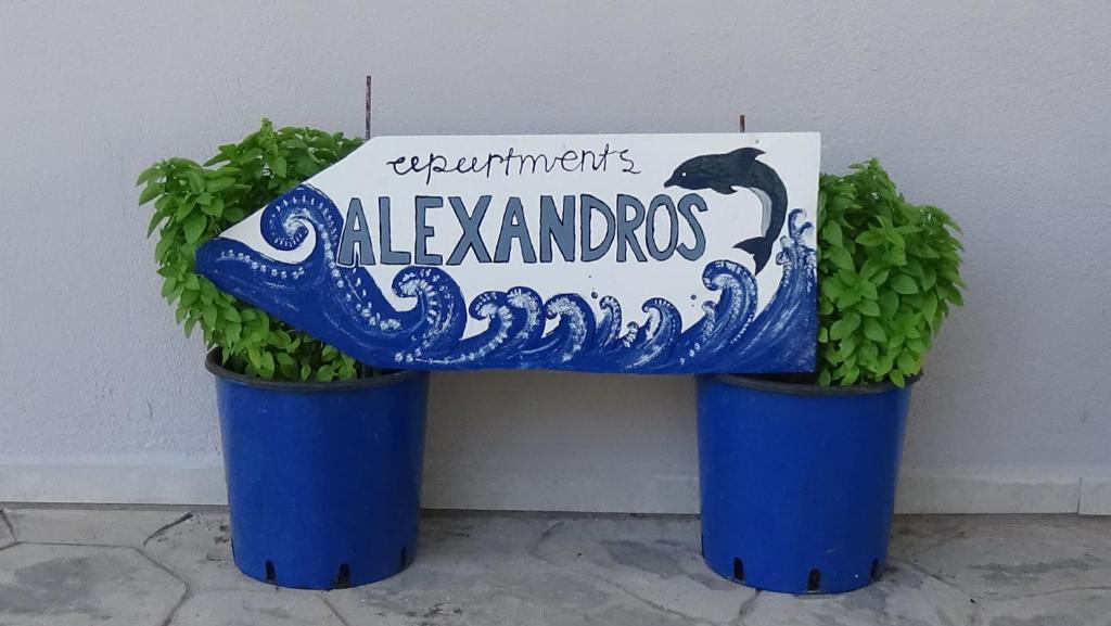 twee potplanten naast een bank met een bord bij Alexandros Apartments in Dhrepanon