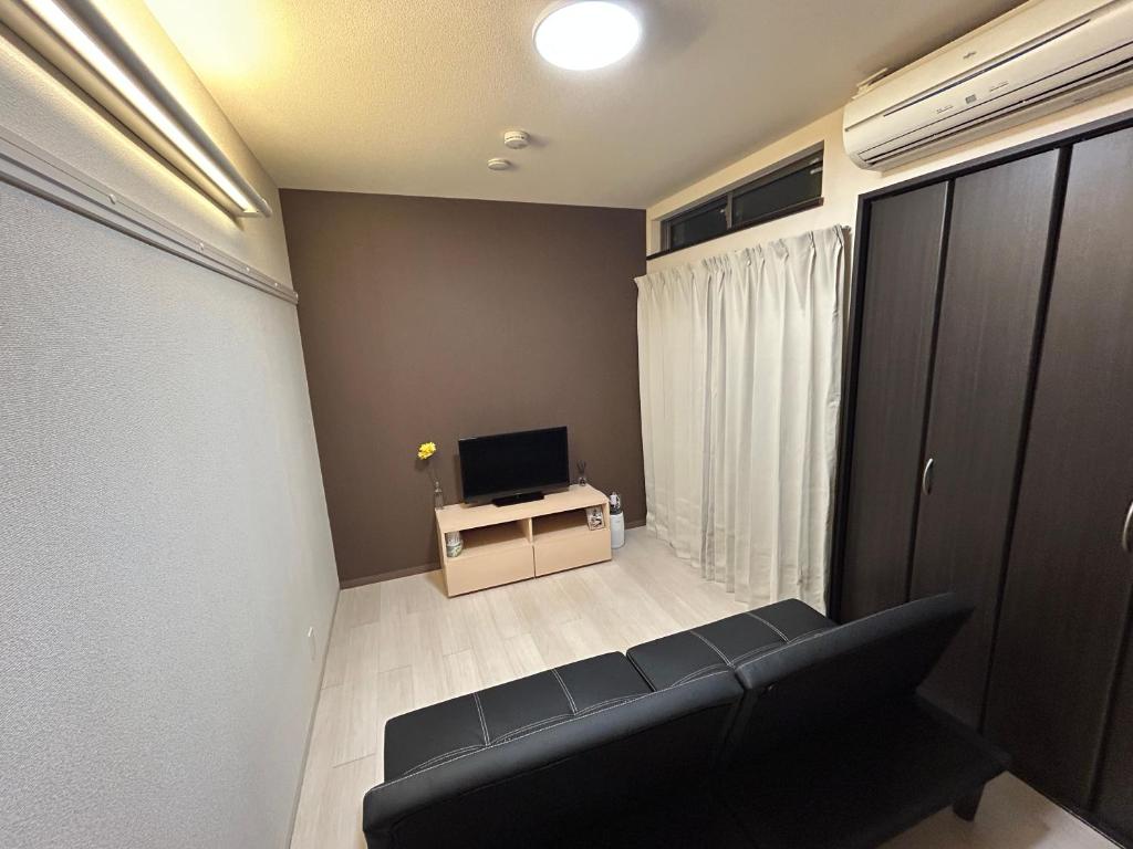 a living room with a couch and a television at Guest House Ogusu INN in Fukuoka