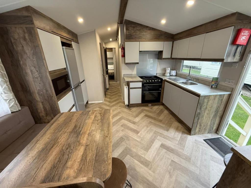 eine kleine Küche mit einem Holztisch in einem Zimmer in der Unterkunft Oscars Inn, West Sands, Seal Bay Resort in Selsey