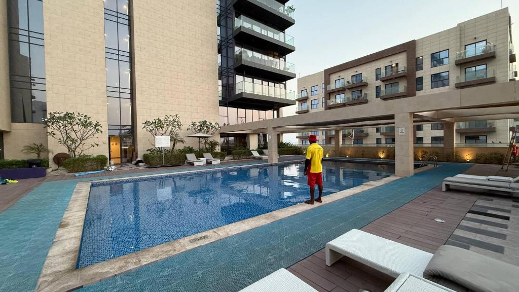 a man standing next to a swimming pool in a building at Sea-View 1BR in Saadiyat - Pool - GYM - Free Parking in Abu Dhabi