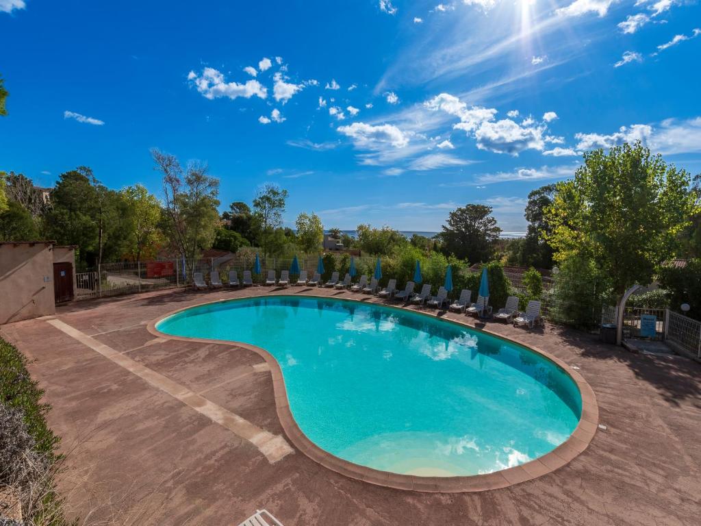 a swimming pool with chairs and umbrellas at Vacancéole - Résidence Lisa Maria in Favone
