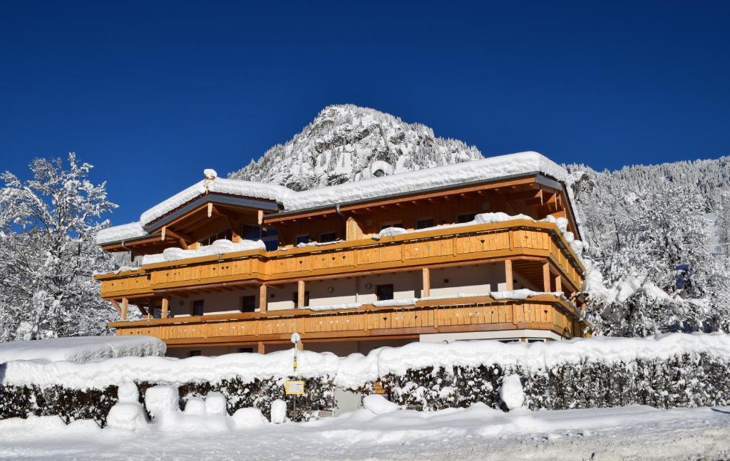 a building covered in snow in front of a mountain at Chalet Hirschbach in Bad Hindelang