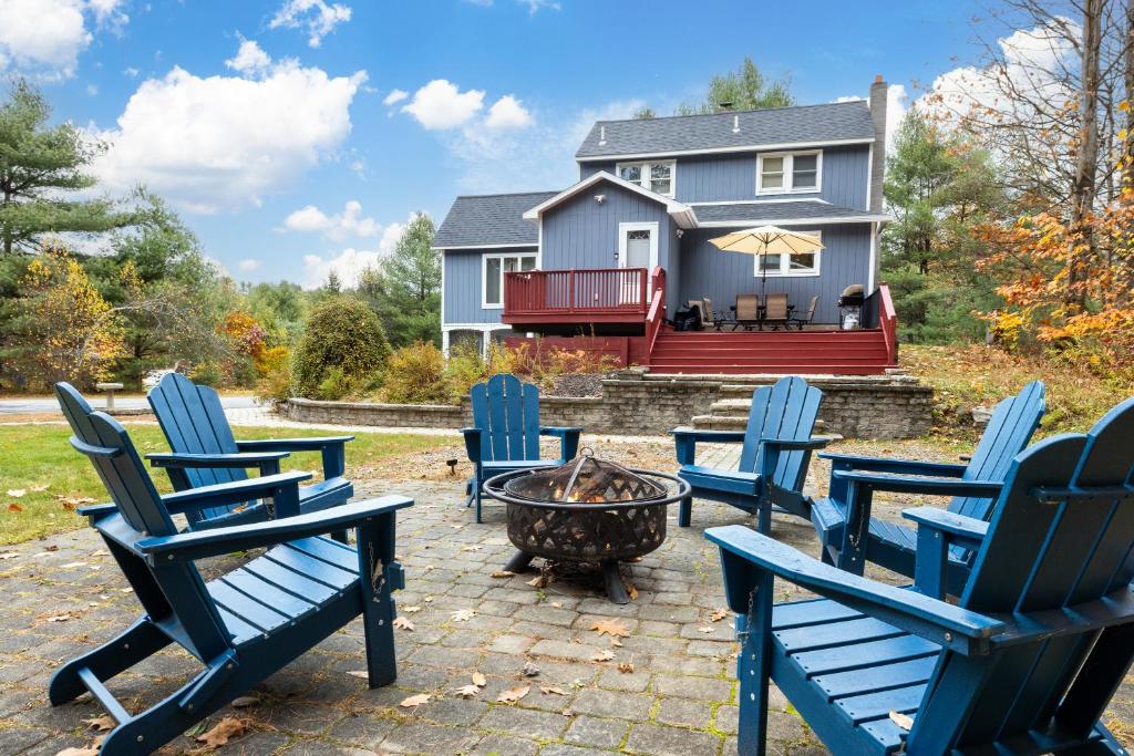 a group of chairs around a fire pit in front of a house at 3BR Lake Luzerne Retreat with Game Room & Hot Tub in Lake Luzerne