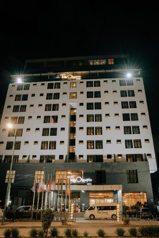 a large white building with a car in front of it at Tolip Olympia Hotel in Addis Ababa
