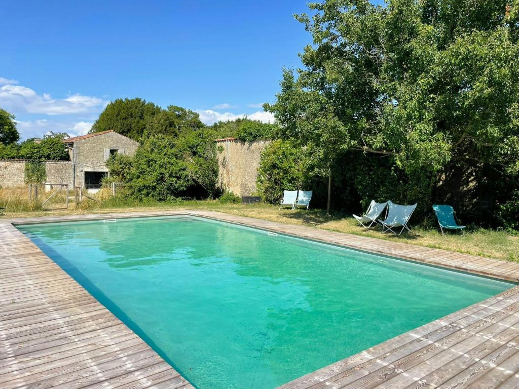a swimming pool with two chairs and a house at Restored Farm Estate Near Atlantic Coast France in La-Gripperie-Saint-Symphorien