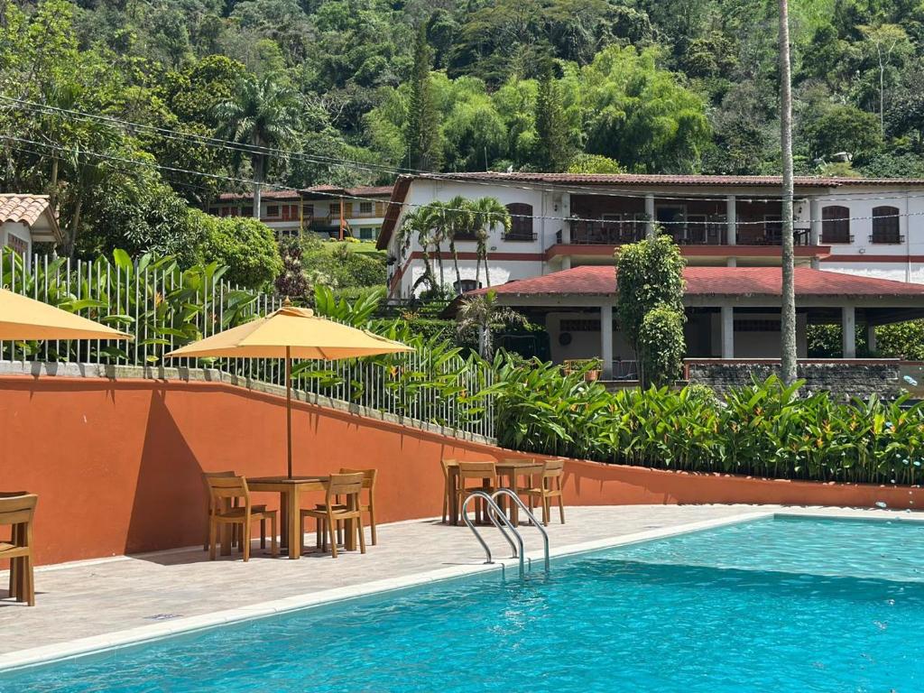 a pool with tables and chairs next to a building at Granja del Cafe Hotel y Centro de convenciones in Venecia