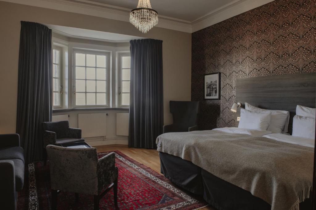 a bedroom with a bed and a chair and a window at Home Hotel Grand Helsingborg in Helsingborg