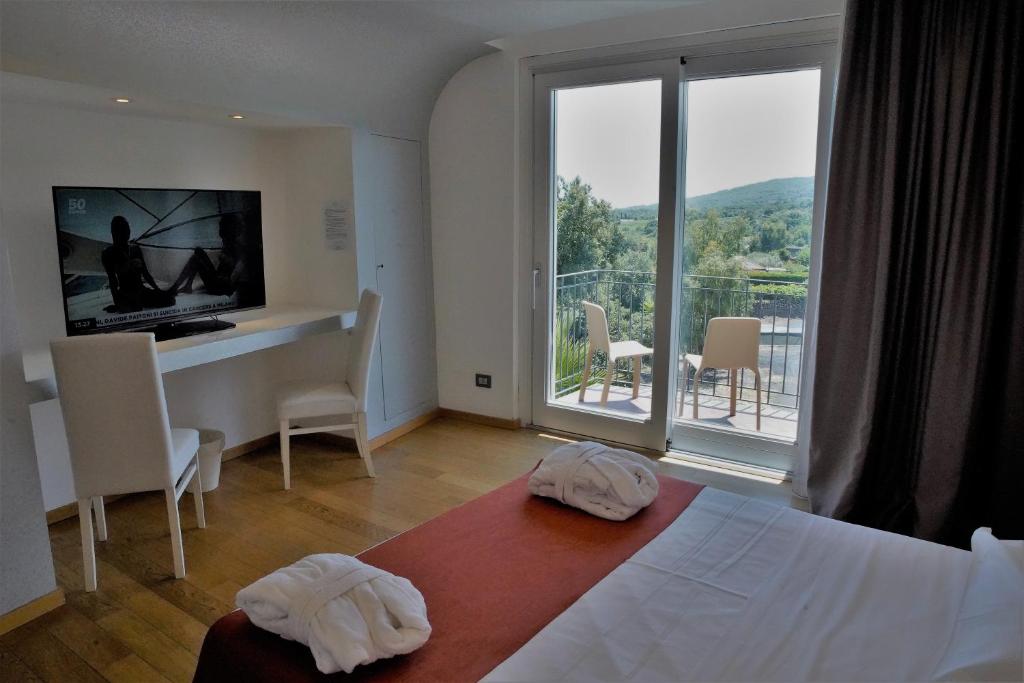 una camera con letto, scrivania e balcone di Mareneve Resort a Linguaglossa
