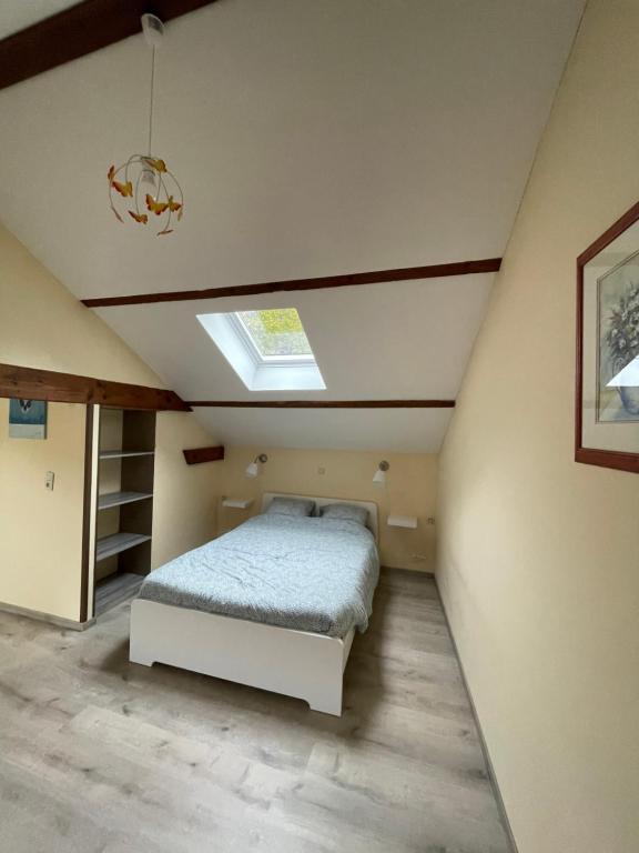 een slaapkamer met een bed en een dakraam bij L'évasion in Bouillon