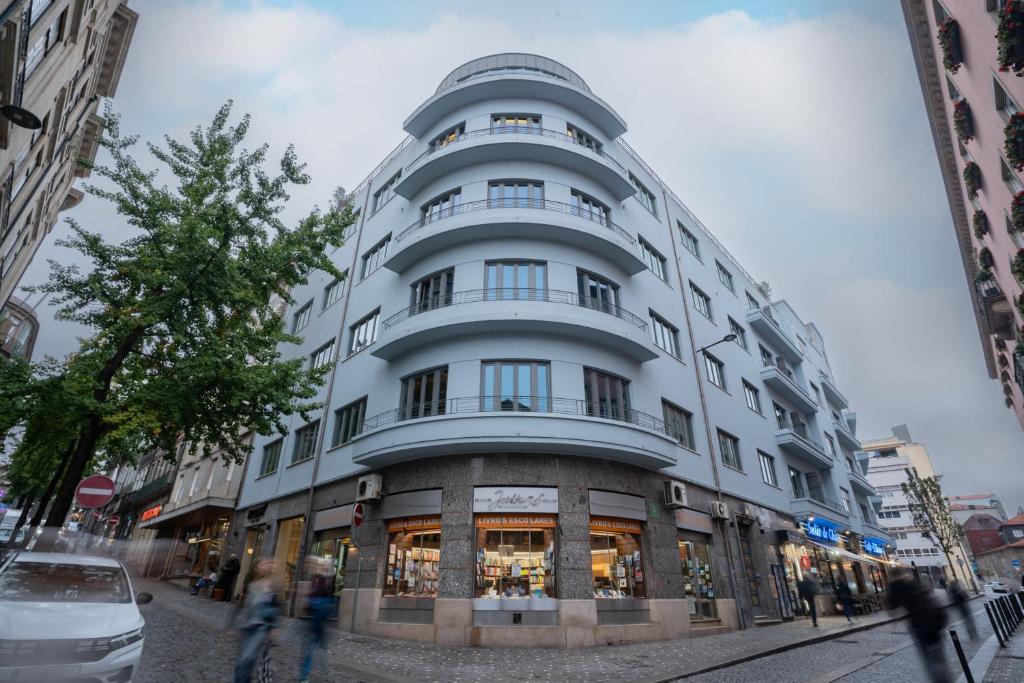 a tall white building with people walking in front of it at Akeah Porto Centro in Porto