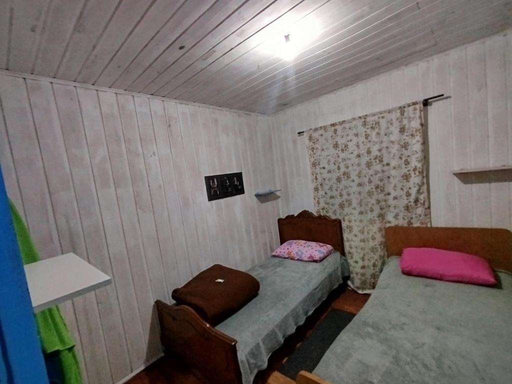 a small room with two beds and a table at Quarto com duas Camas Individuais in Gramado