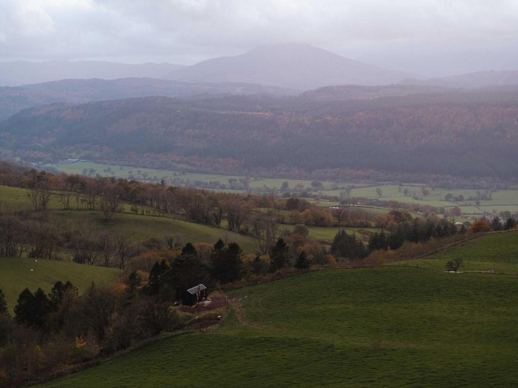 a view of a green field with trees and mountains at Ascella in Llanrwst