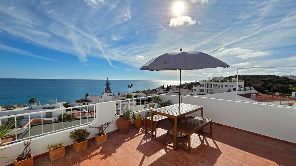 a table on a balcony with an umbrella at Margarida Seaview Terrace Apartment in Luz