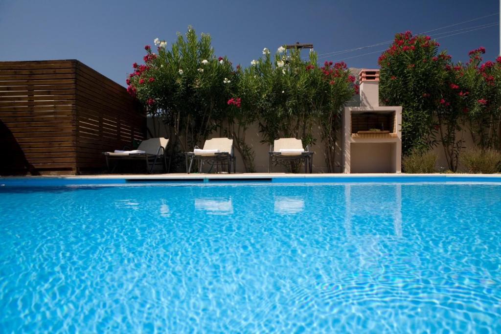 a large blue swimming pool with chairs and flowers at Le Torri Villas by Nidri holiday villas in Nydri