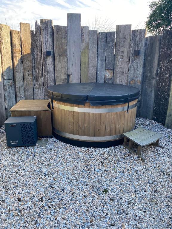 a hot tub and a bench in front of a fence at Van Egmond suites Mr Blue Sky in Anna Paulowna