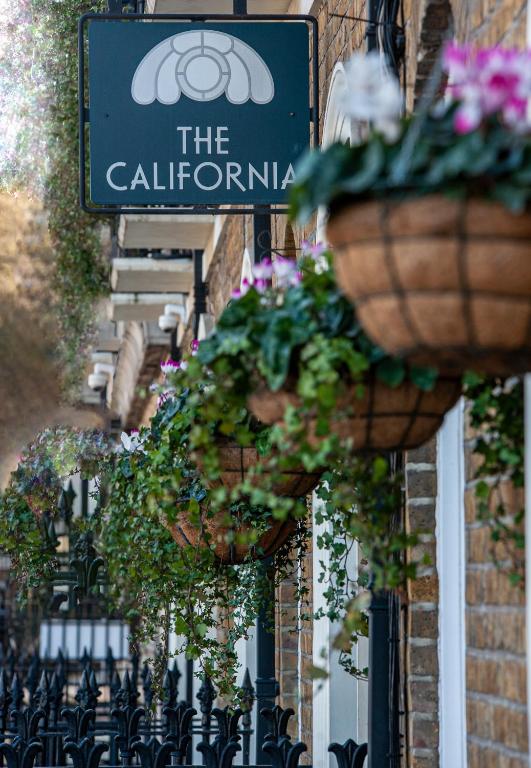a sign on a building with potted plants on it at The California - London Kings Cross in London