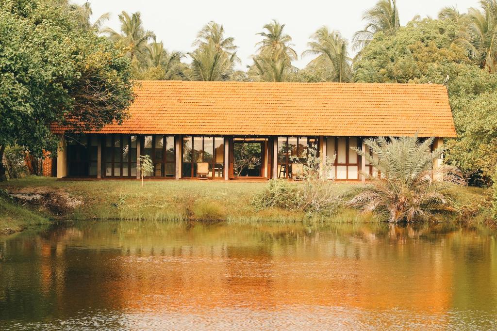 a house with an orange roof next to a body of water at Panai Adi Boutique Villa in Kuravankudil