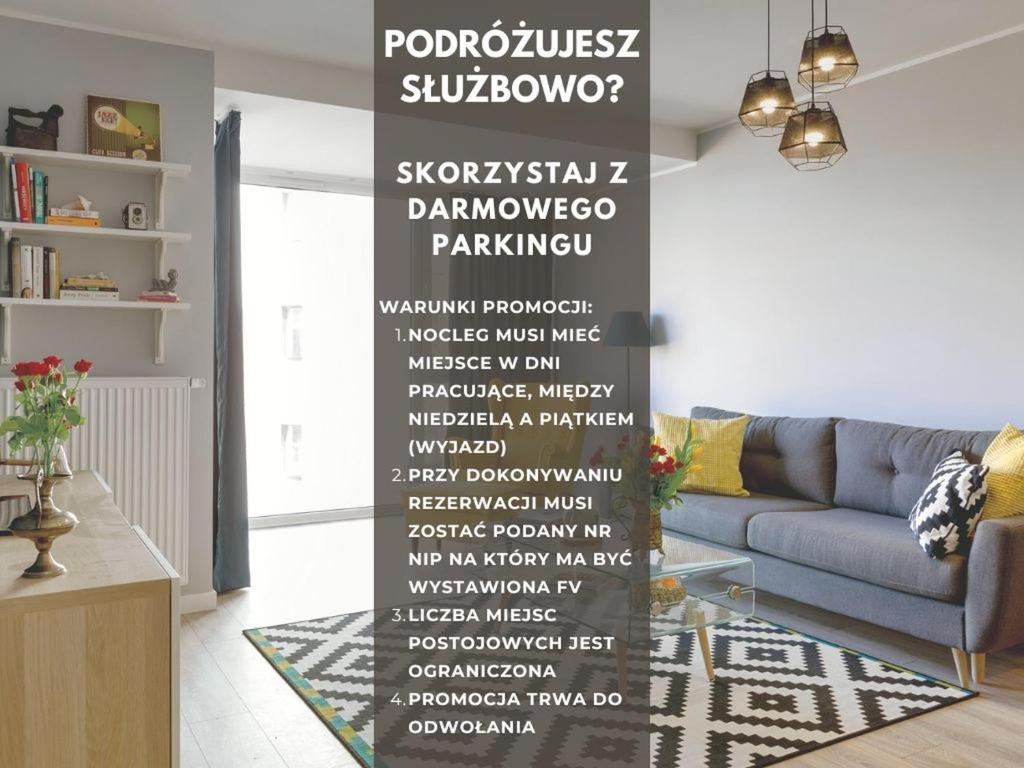 a living room with a blue couch and a wall with a sign at Littleheaven Studia & Apartmenty in Gdańsk