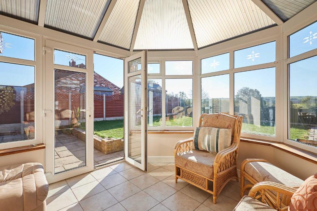 a screened in porch with a chair and windows at Host & Stay - Cherry Willows in Stainsacre