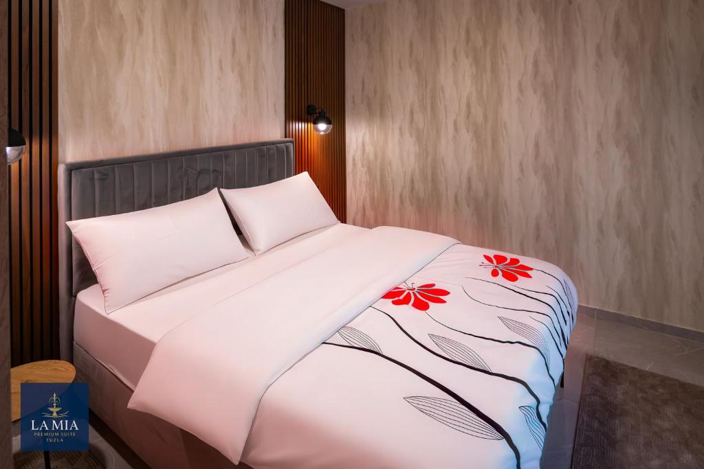 een bed met witte lakens en rode bloemen erop bij La Mia Premium Suite in Tuzla