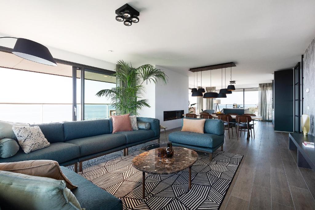 ein Wohnzimmer mit blauen Sofas und einem Tisch in der Unterkunft Droomsuites Egmond aan Zee 8 personen by Droomvilla in Egmond aan Zee