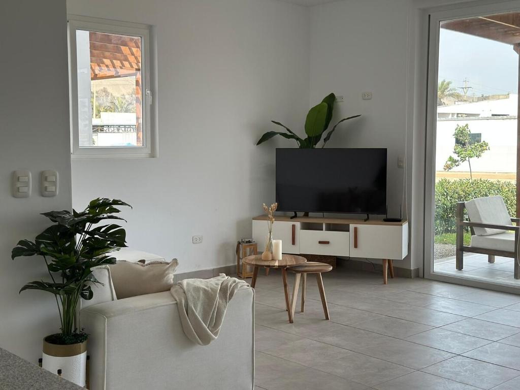 a living room with a tv and a couch and a table at Beach House - Private Dock and Pool in Cerro Azul