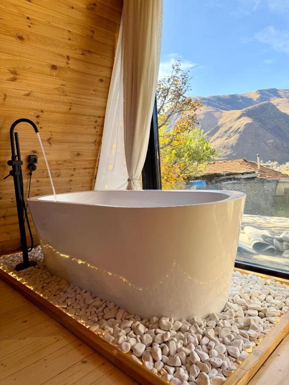 a bath tub sitting in a room with a window at Kuro cottage- A frame in Kazbegi