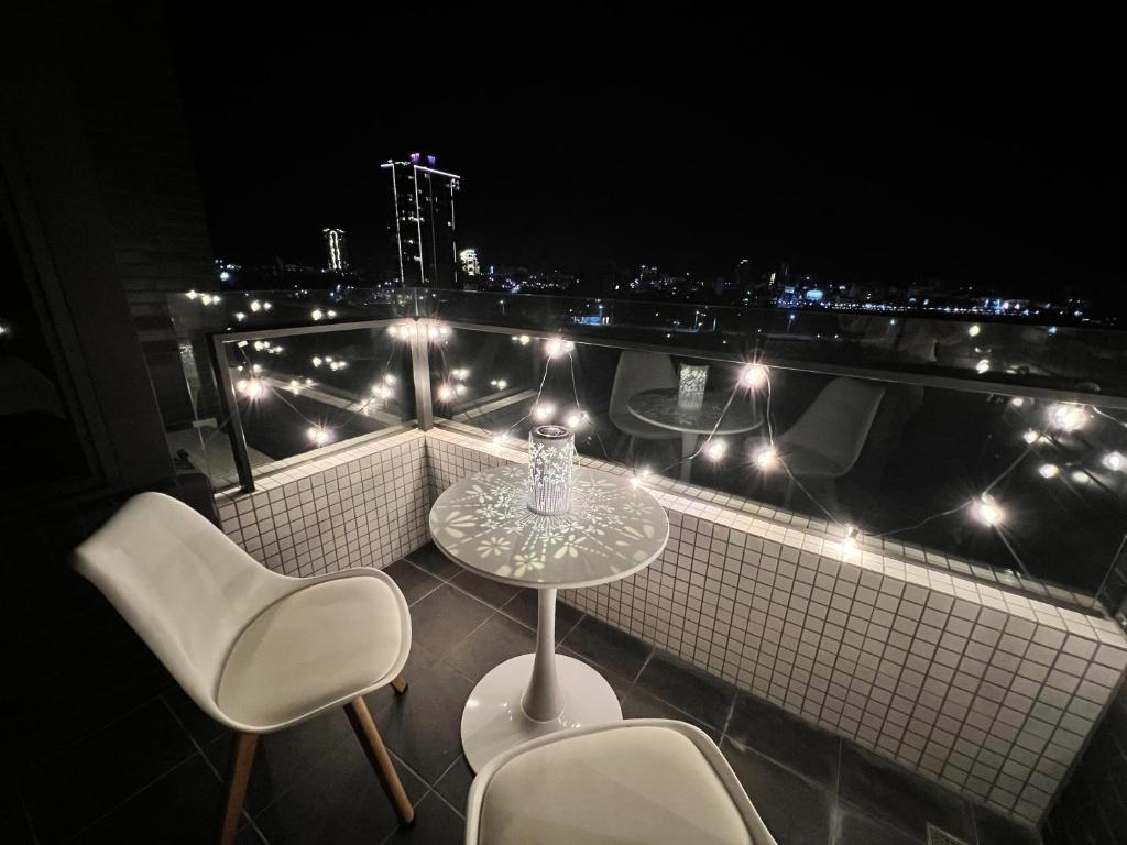 uma mesa e cadeiras numa varanda à noite em 漫遊文旅溫泉宅ㄧ山海景觀陽台房ㄧ晚上6點入住ㄧ晚進晚退一21小時睡飽飽方案 em Toucheng