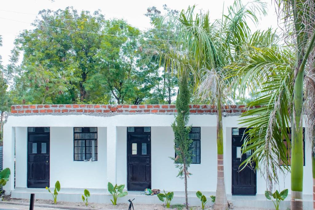 a white house with black doors and palm trees at Lake View Suites, Homa Bay in Homa Bay