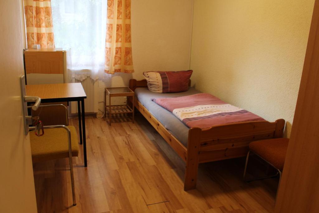 a small bedroom with a bed and a table at Bungalow 1 - 4-Raum-Wohnung mit Küche und 2 WC Duschen in Ohrdruf-Crawinkel in Ohrdruf