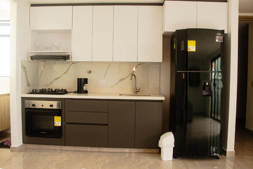 a kitchen with white cabinets and a black refrigerator at Frente a Viva Envigado, AC, moderno e iluminado in Envigado