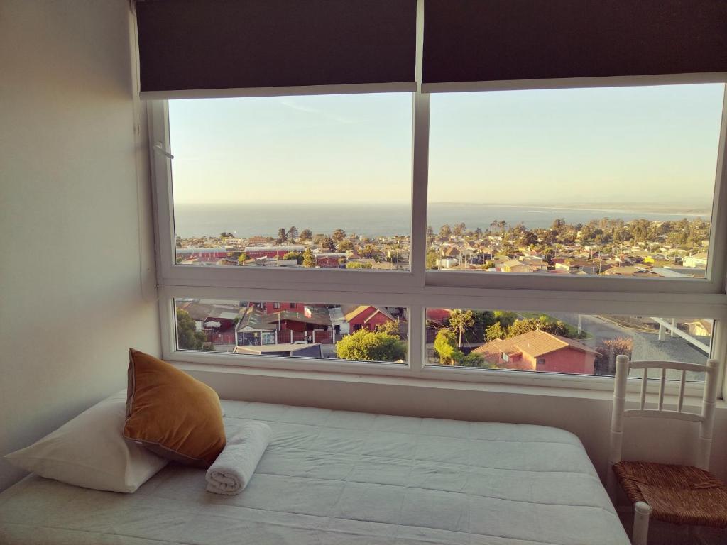 a bed in a room with a large window at Despierta con vista al mar en un hogar tranquilo y luminoso in Concón