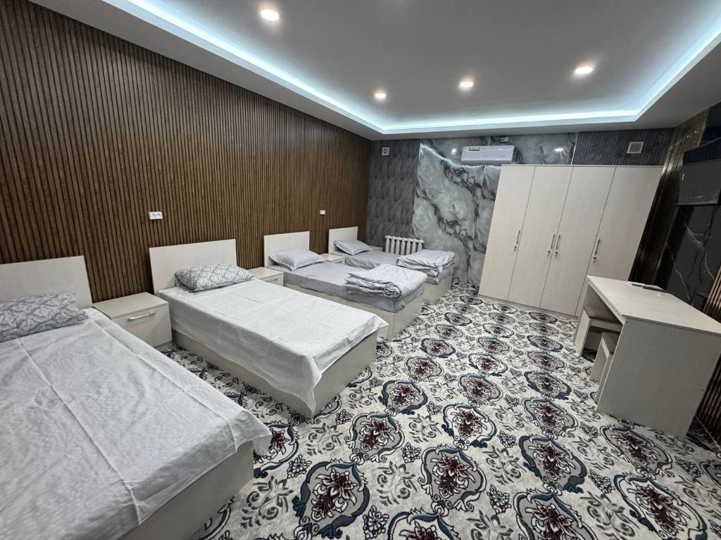 a room with three beds and a desk at Amiriy hostel in Bukhara