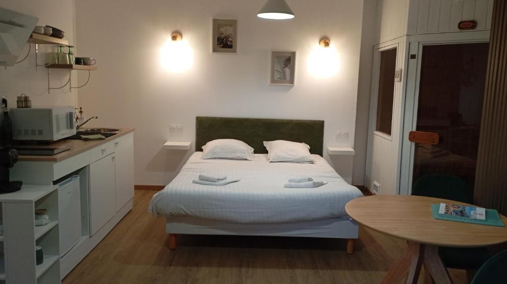 um pequeno quarto com uma cama e uma mesa em Le cocon des Rosies le Eleanor Roosevelt em Colleville-sur-Mer