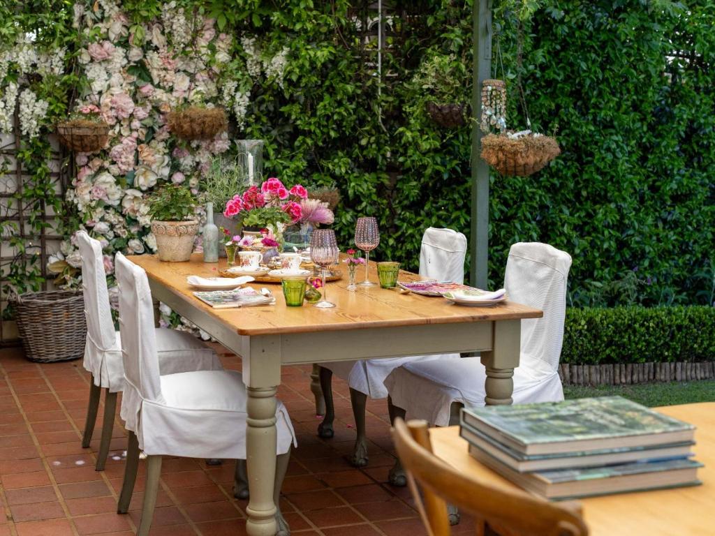 a wooden table with white chairs and flowers on it at Villa Puccini in Cape Town