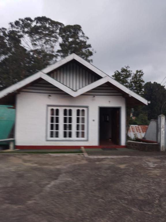 a small white house with a large window at Nehara Inn in Nuwara Eliya