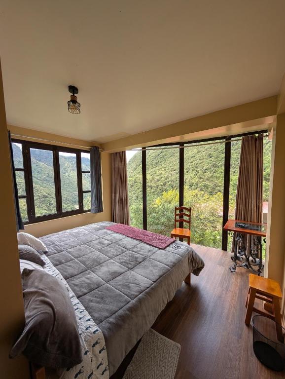 a bedroom with a large bed and large windows at TUMI Villa Salkantay in Colcapampa
