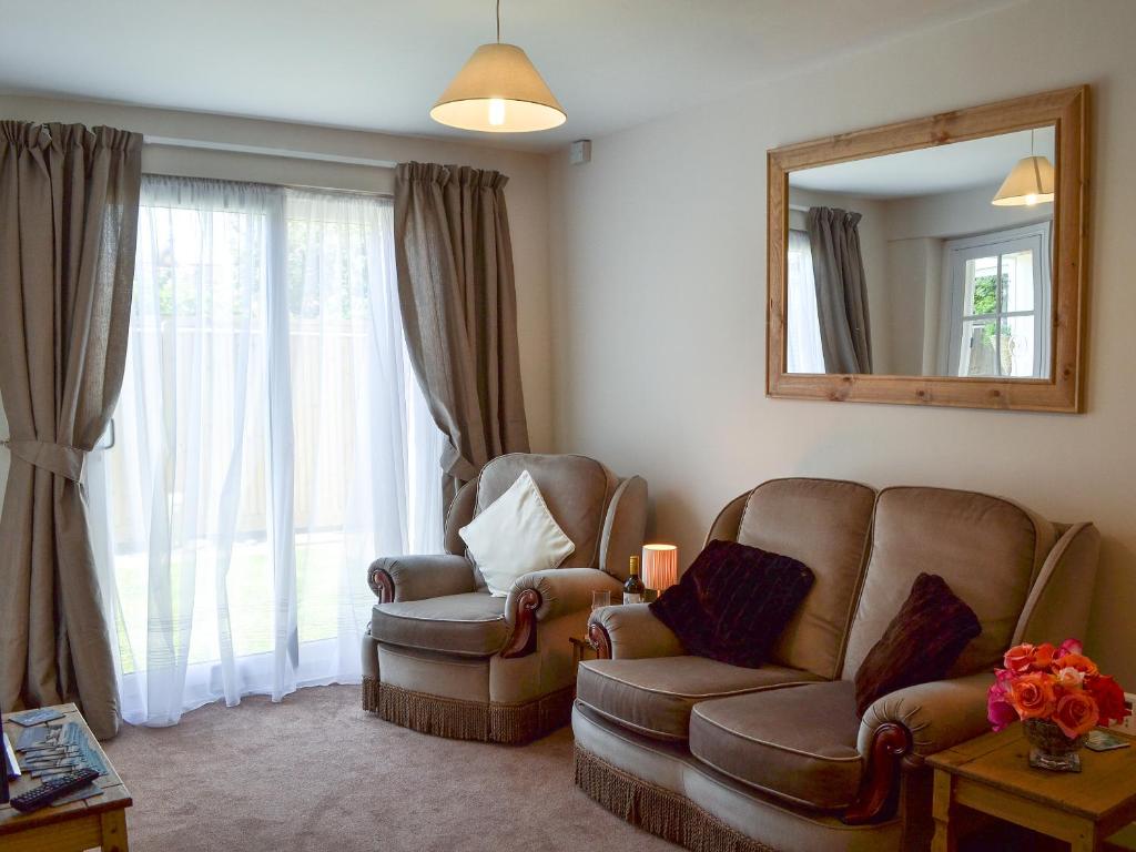 Una sala de estar con dos sillas y un espejo. en The Cabin, en Pevensey