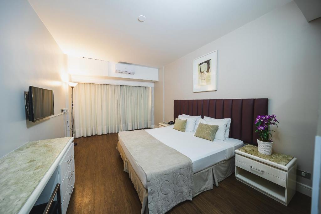 a hotel room with a large bed and a television at Hotel Victoria Villa Curitiba by Nacional Inn in Curitiba