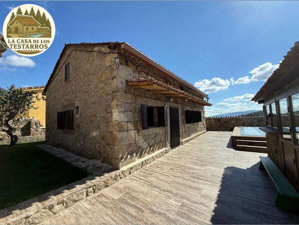 Un gran edificio de piedra con una terraza de madera. en La Casa de los Testarros, en Gavilanes