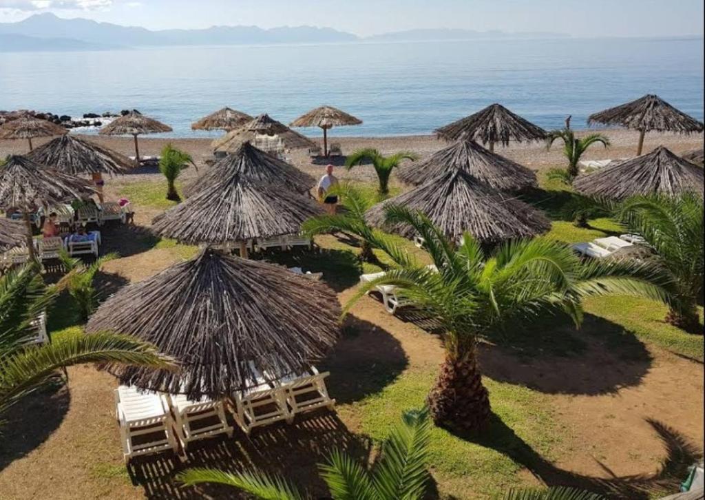 a beach with some straw umbrellas and the ocean at Dimitra's Little Beach House paradise by "elite" in Petalidhion