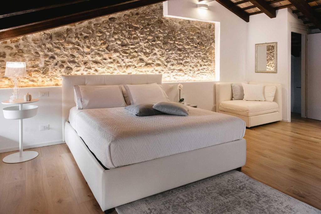 a bedroom with a large white bed and a chair at Affittacamere CASA DOLCE CASA SAN DANIELE in San Daniele del Friuli