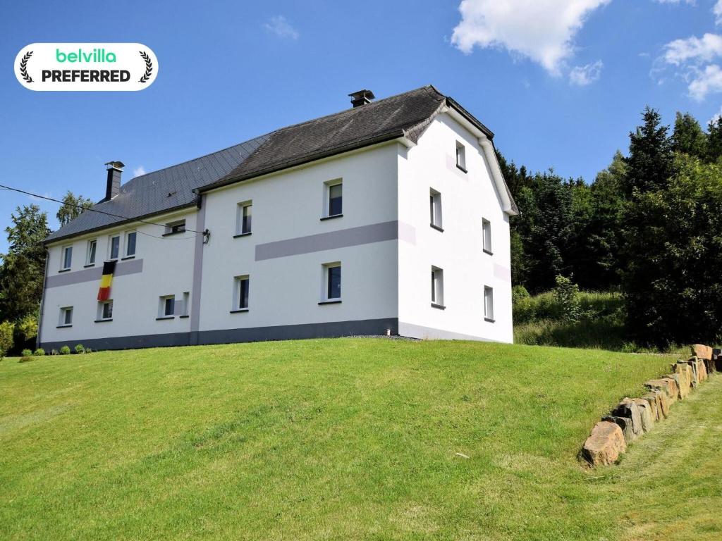 a large white building on a grassy hill at Holiday Home in Saint Vith with Terrace in Schoenberg